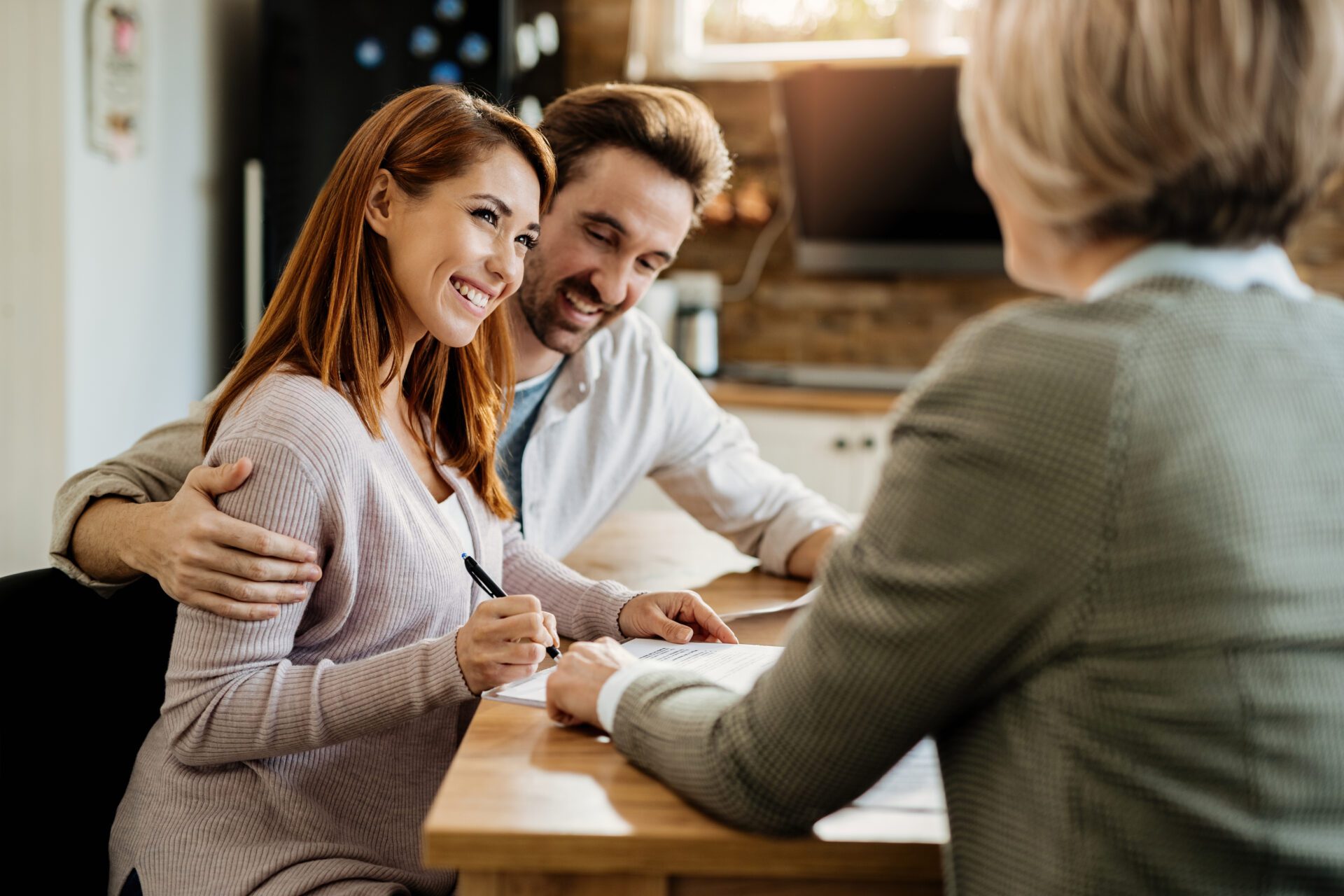 Happy couple signing a contract during a meeting with financial advisor. Car Insurance Form Accidental Concept